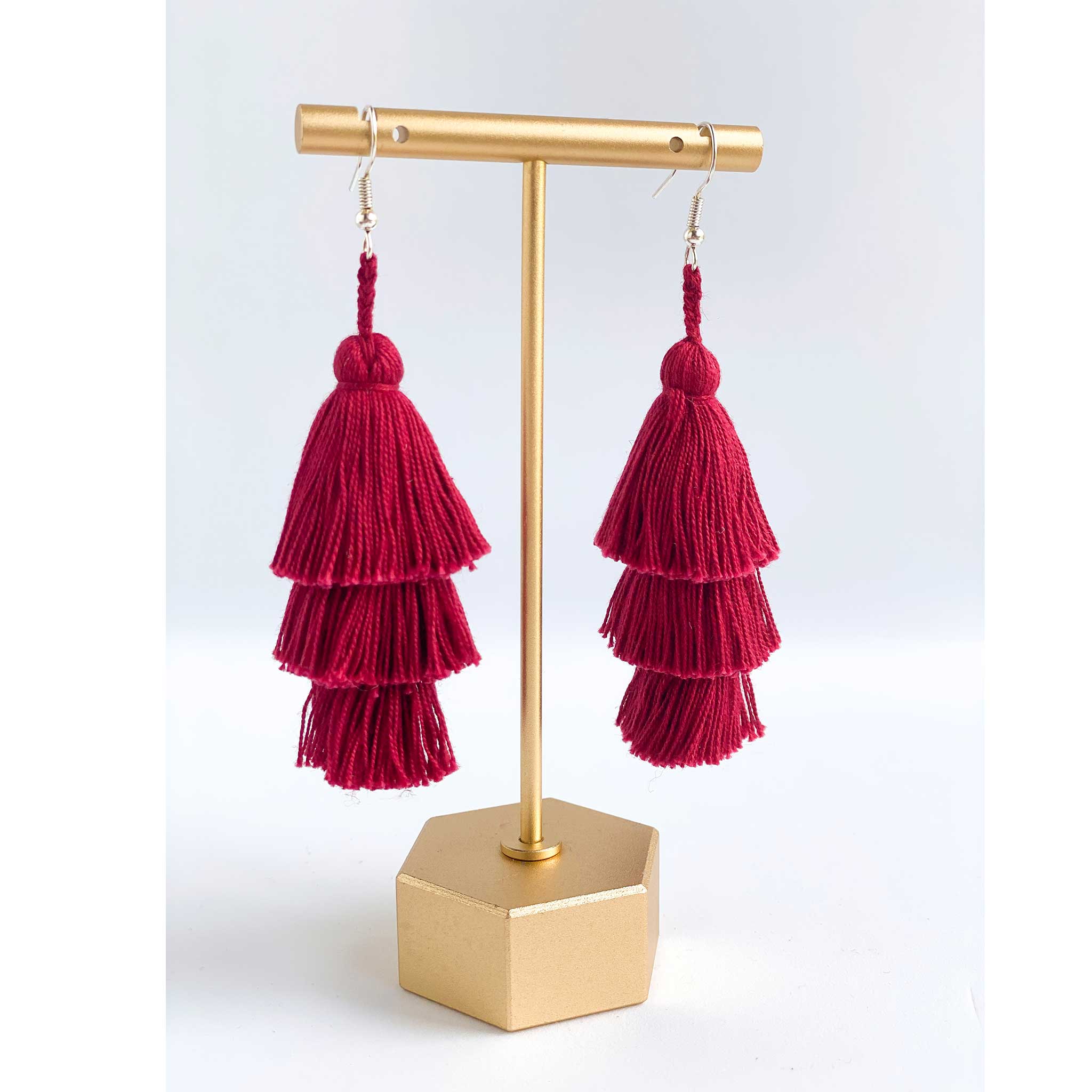 3-tiered tassel earrings in burgundy hanging from a jewelry display