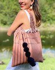Woman carrying over her shoulder the Handwoven-Loom-Tote-Bag-in-Mauve-in-Navy-Stripes