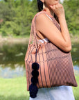 Lifestyle image of women carrying over her shoulder the Handwoven-Loom-Tote-Bag-in-Mauve-in-Navy-Stripes