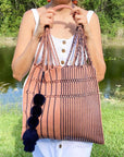Woman carrying over her shoulder the Handwoven-Loom-Summer-Tote-Bag-in-Mauve-in-Navy-Stripes